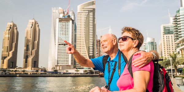 active senior couple on sightseeing tour in dubai marina, senior man pointing